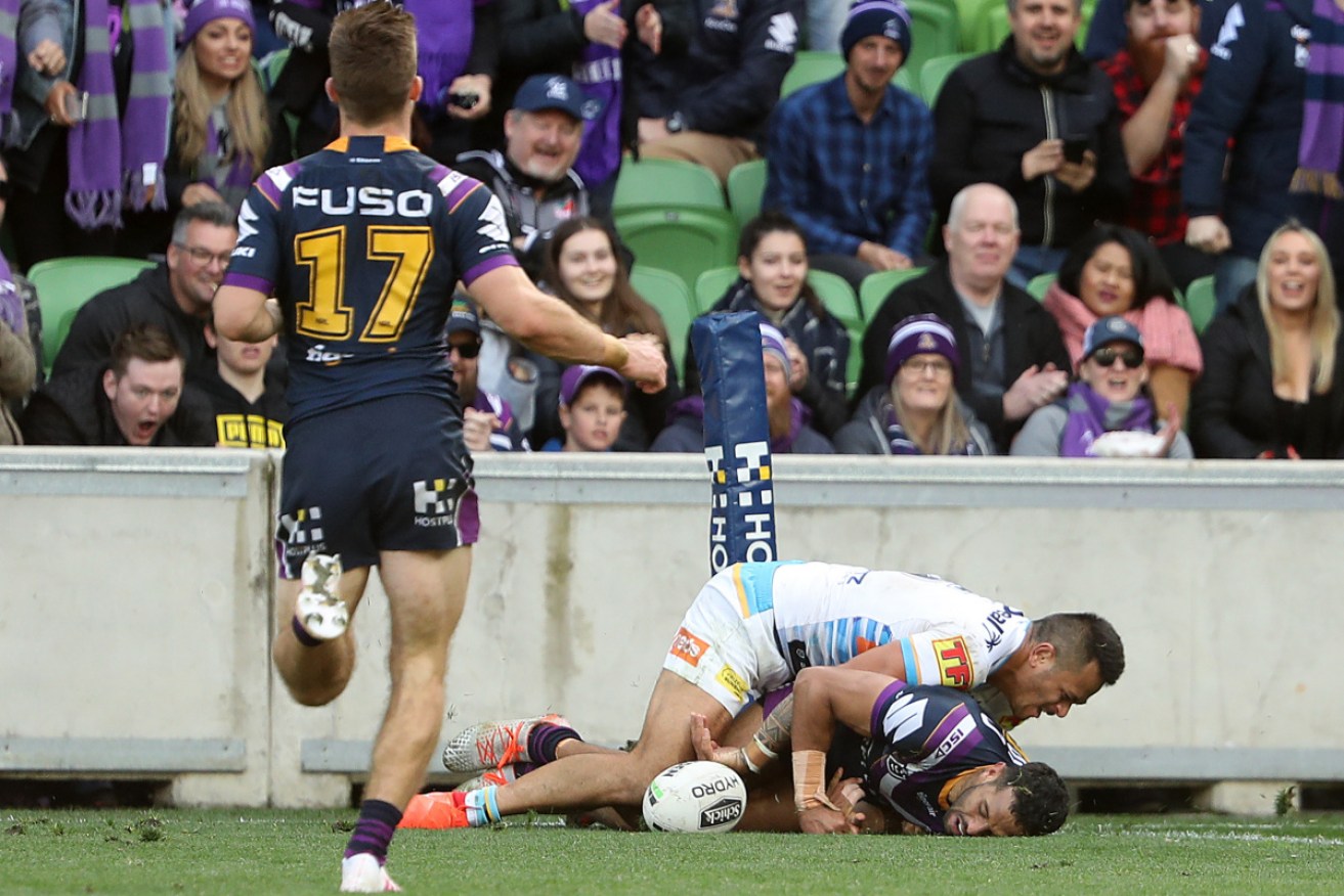 Storm's Josh Addo-Carr is tackled by Phillip Sami after being run down by the Gold Coast speedster. 
