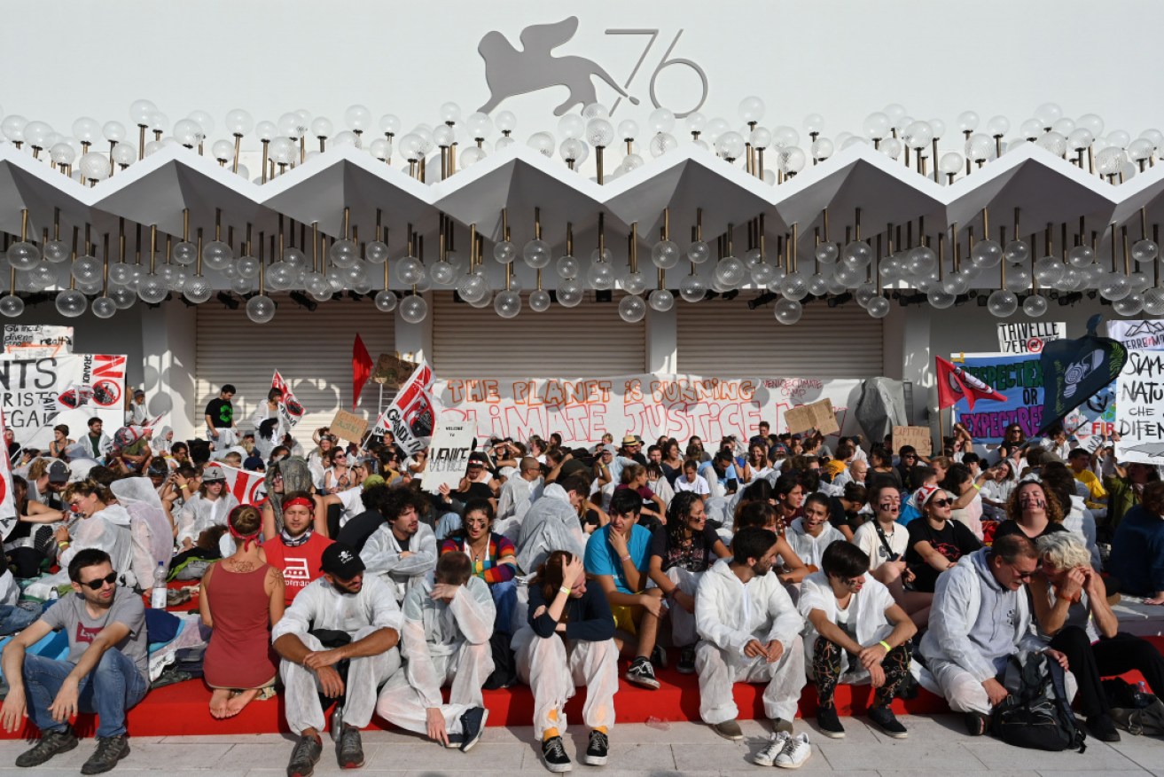 About 300 demonstrators wearing boiler suits have taken over the red carpet at the Venice Film Festival.
