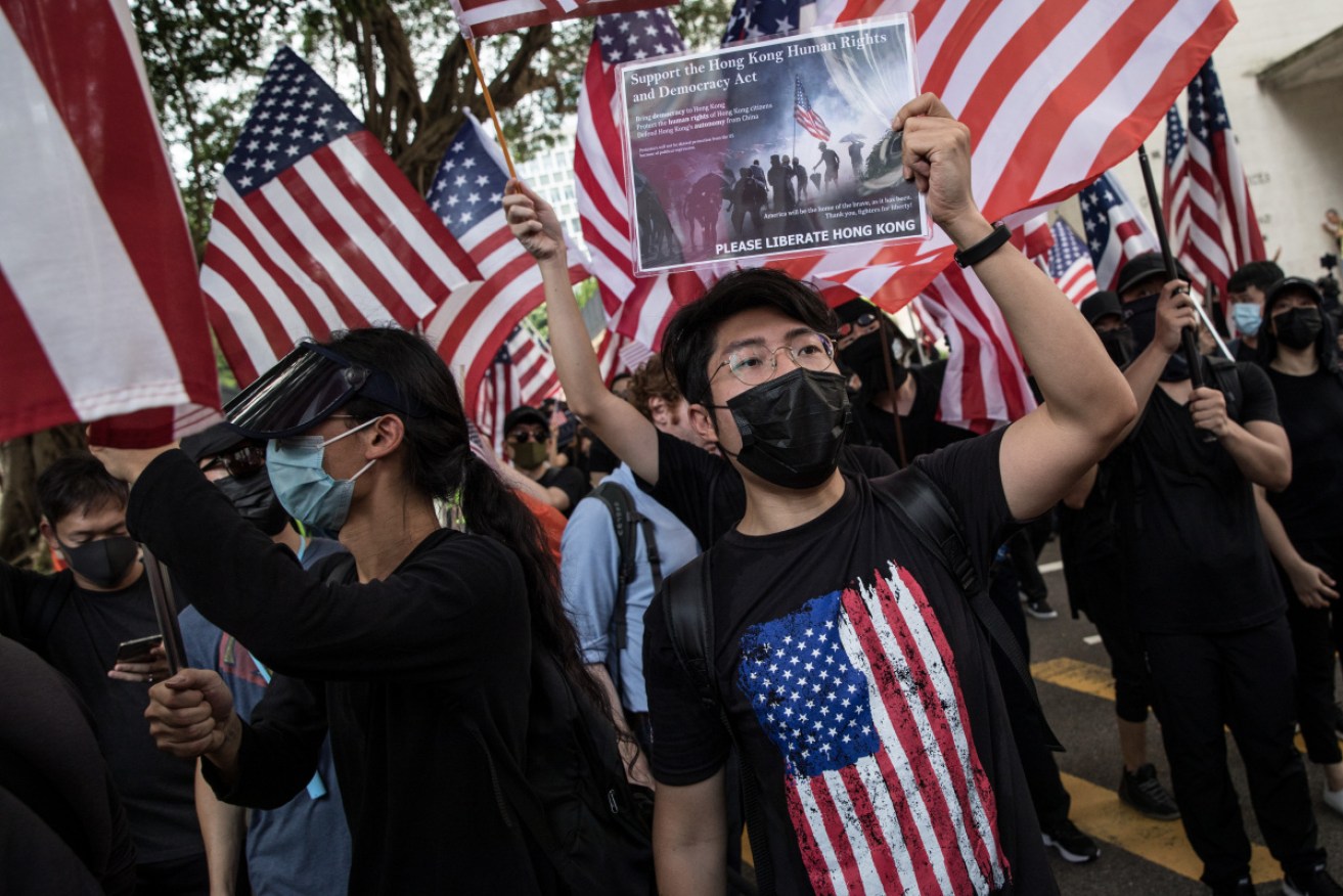 Masked protesters hold American flags as they call on the US to support their demand for democratic reforms. <i> Photo: Getty</i>