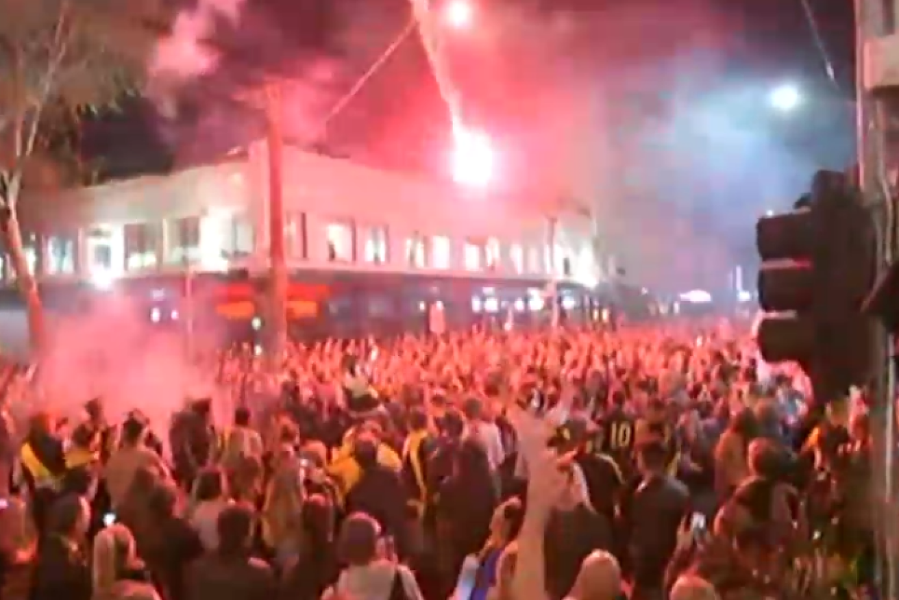A flare arcs into the Swan Street crowd as rowdy Tigers supporters keep police busy late into the night.