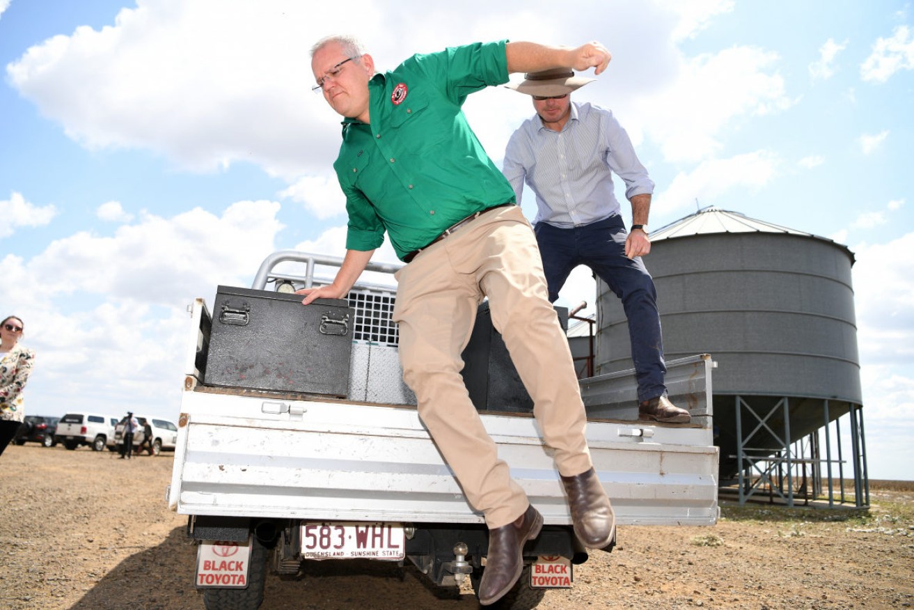 Scott Morrison jumps off the back of a ute during a visit to farms in Queensland on Friday.  