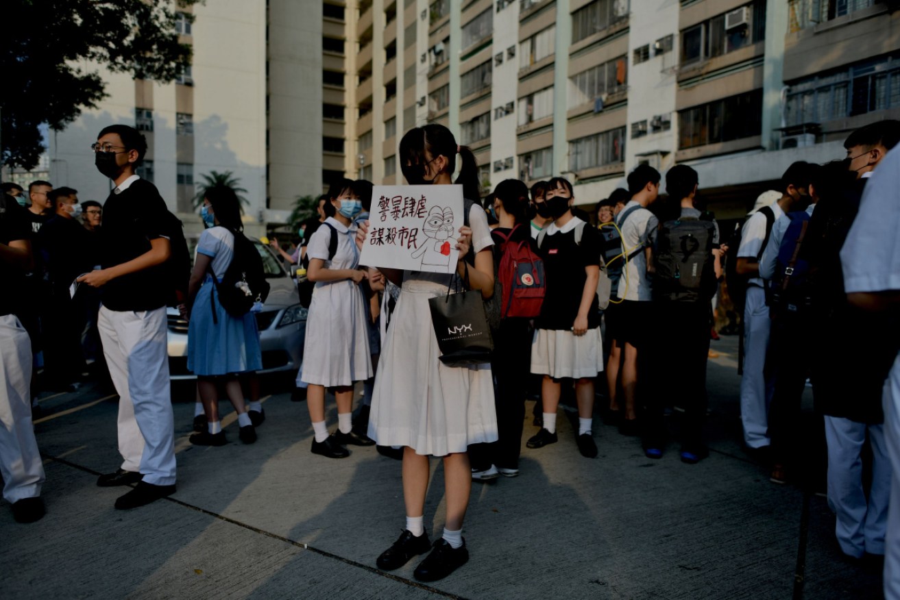 A schoolmate of Tsang Chi-kin, who was shot on October 1, holds a placard saying "police mistreat and murder residents".