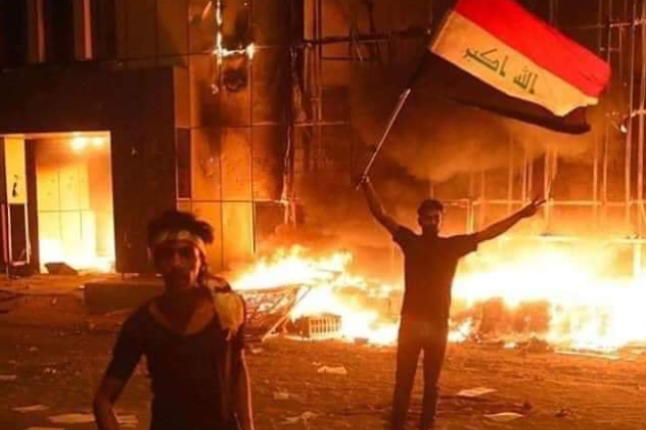 Two young protesters raise the Iraq flag and call for the government to stand down.