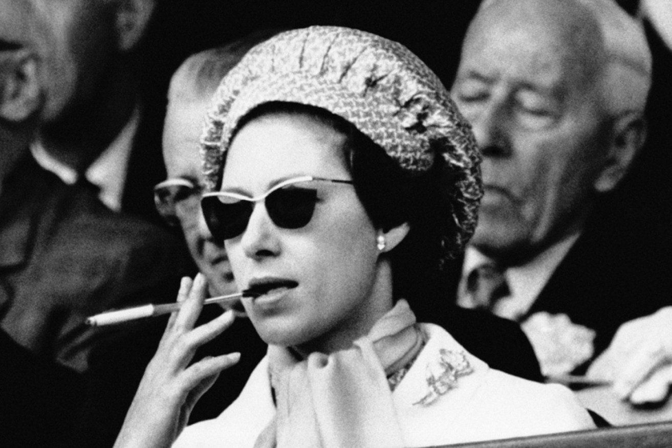 Princess Margaret lights up watching tennis at Wimbledon in July 1965.