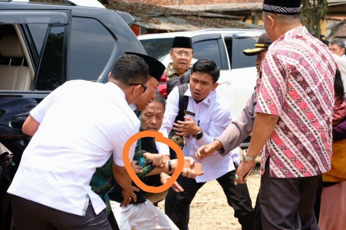 Wiranto falls backwards as the attacker attempts to plunge his blade (circled) deep into the Indonesian minister's chest.