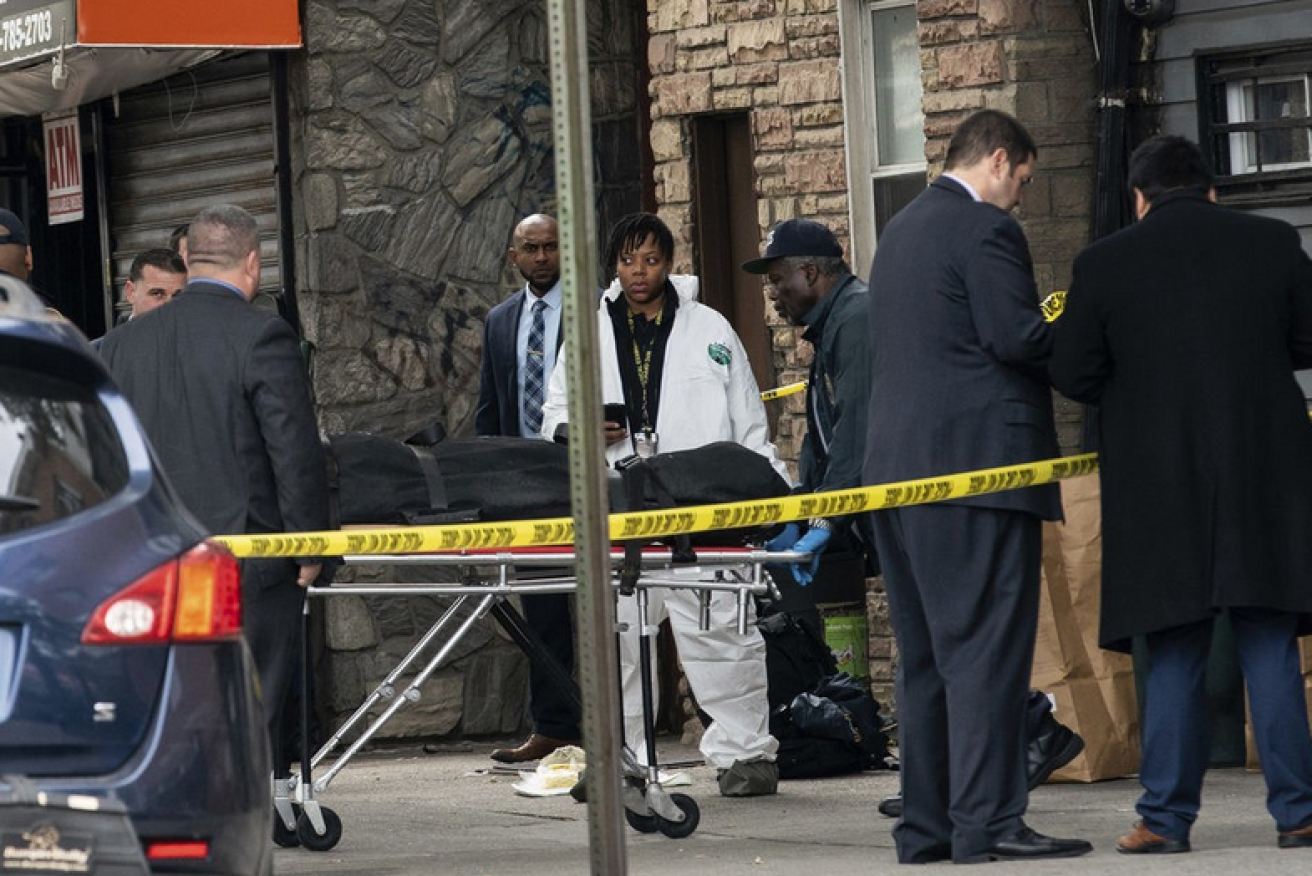 NYPD detectives work the crime scene as the body of another victim is wheeled out.