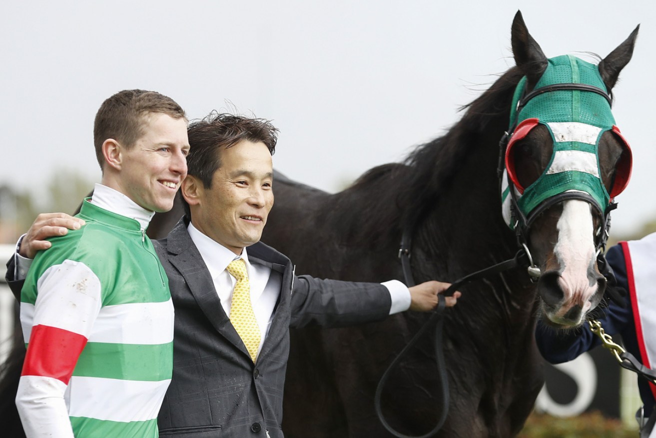 Jockey Damian Lane celebrates with trainer Hisashi Shimizu after riding  Mer De Glace to win the Caulfield Cup. 