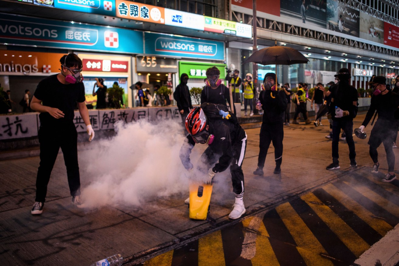 A protester uses a waterproof bag to soak a tear gas canister fired by police.