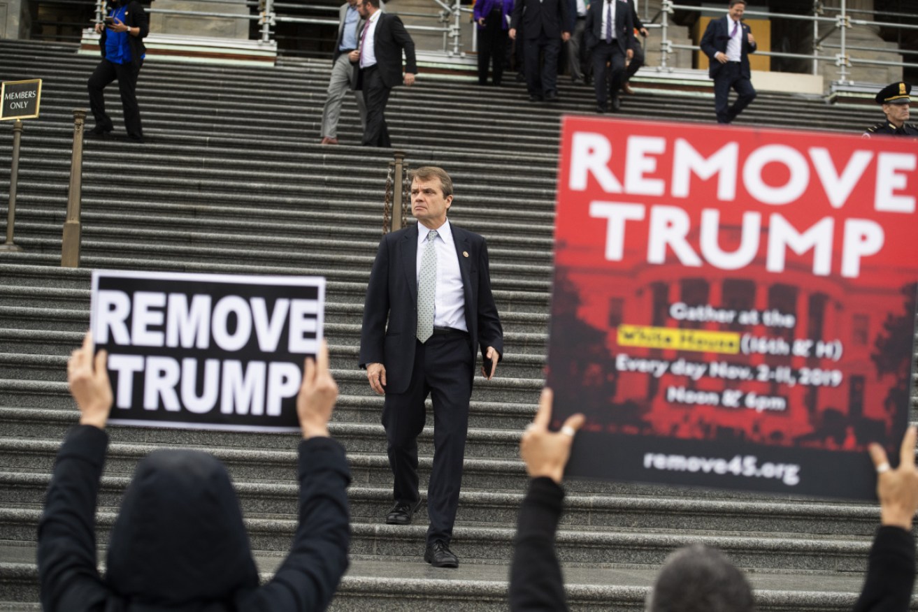 Representative Mike Quigley, D-Ill., walks by protesters outside the Capitol after the House vote on an impeachment inquiry.