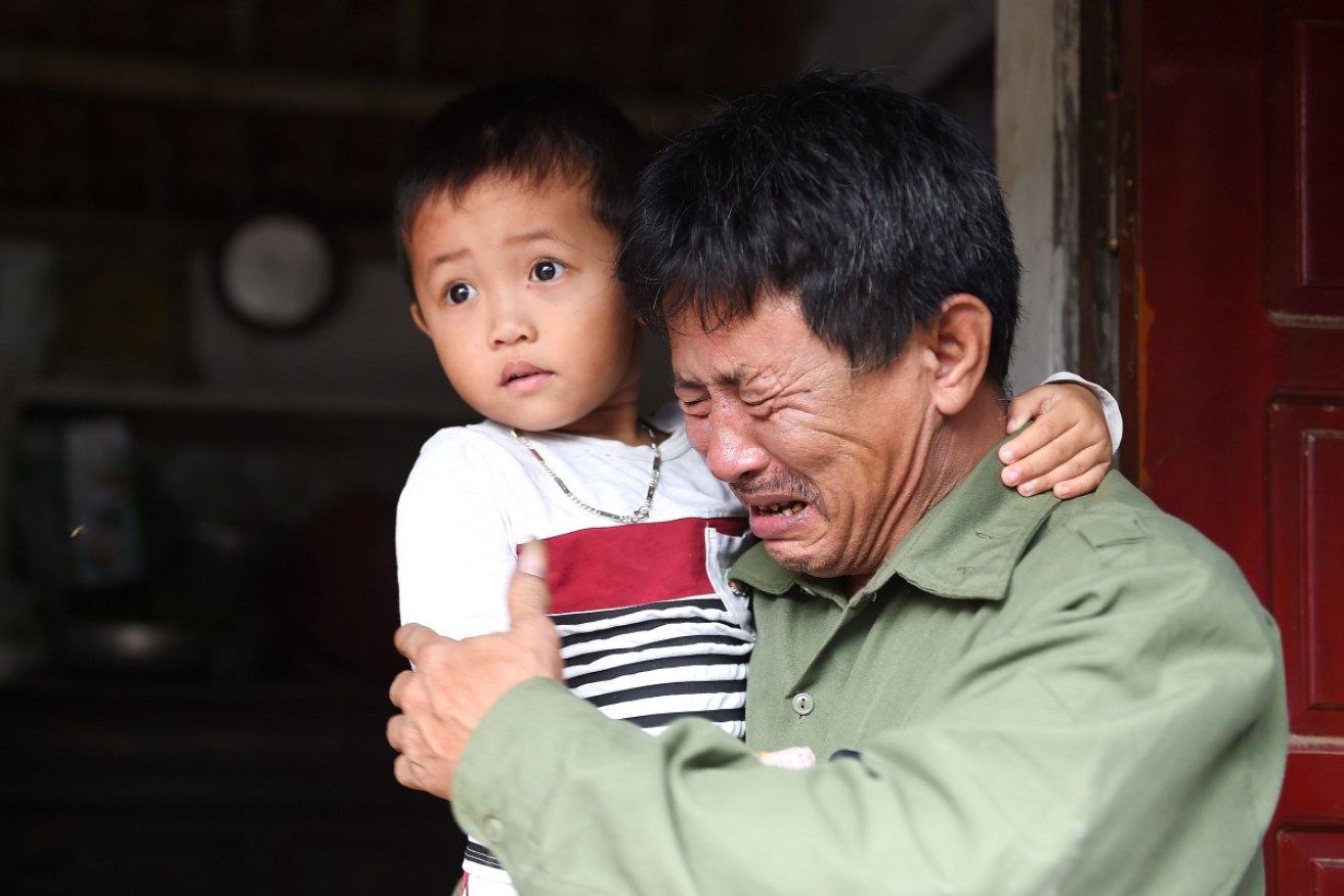 Le Minh Tuan, father of Le Van Ha, cries while holding Ha's son outside their house in Vietnam's Nghe An province.