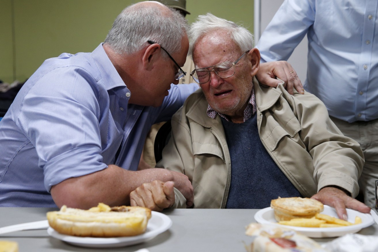 Prime Minister Scott Morrison comforts Owen Whalan who has been evacuated from his home, at Taree Evacuation Centre on Sunday.