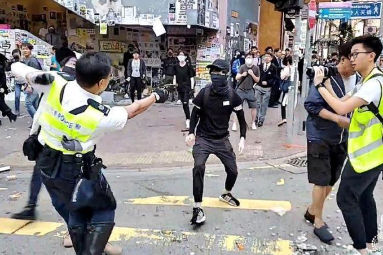 A Hong Kong policeman opens fire on a protester prior  to the elections.