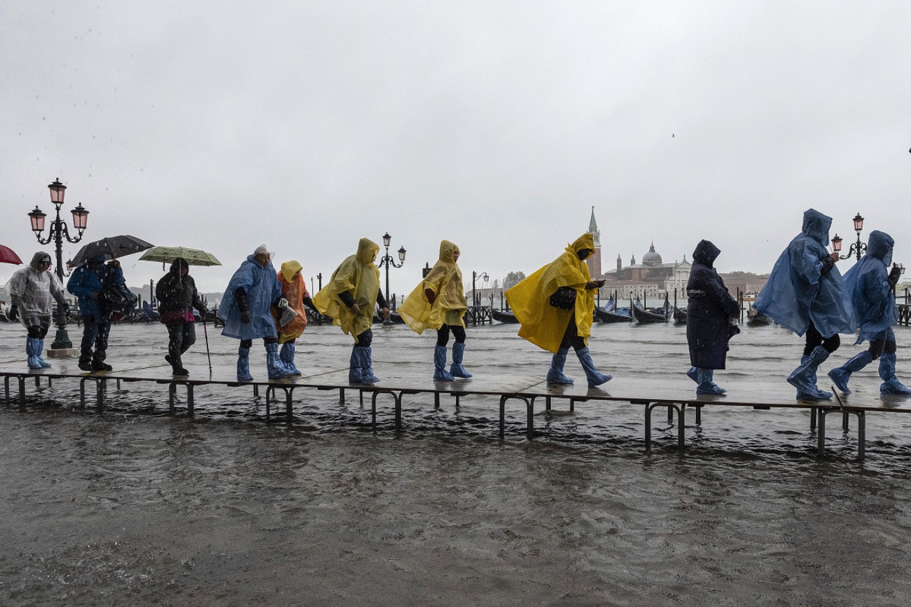 Tourists walk in high water in Piazza San Marco, as the high tide, or acqua alta, grips Venice.