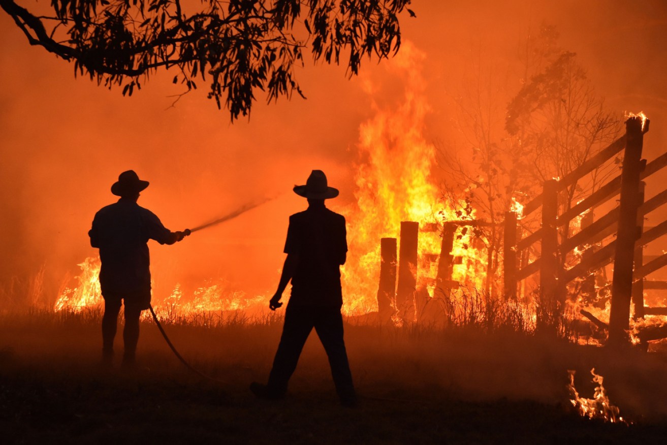 Residents defend a property from a bushfire at Hillsville near Taree on November 16.