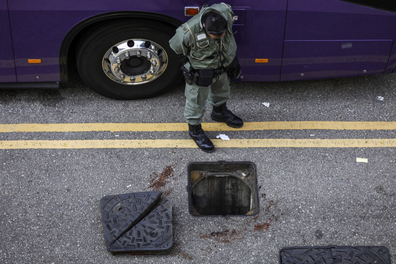 A Hong Kong police officer waits at a manhole after two protesters tried to escape through the sewerage system.