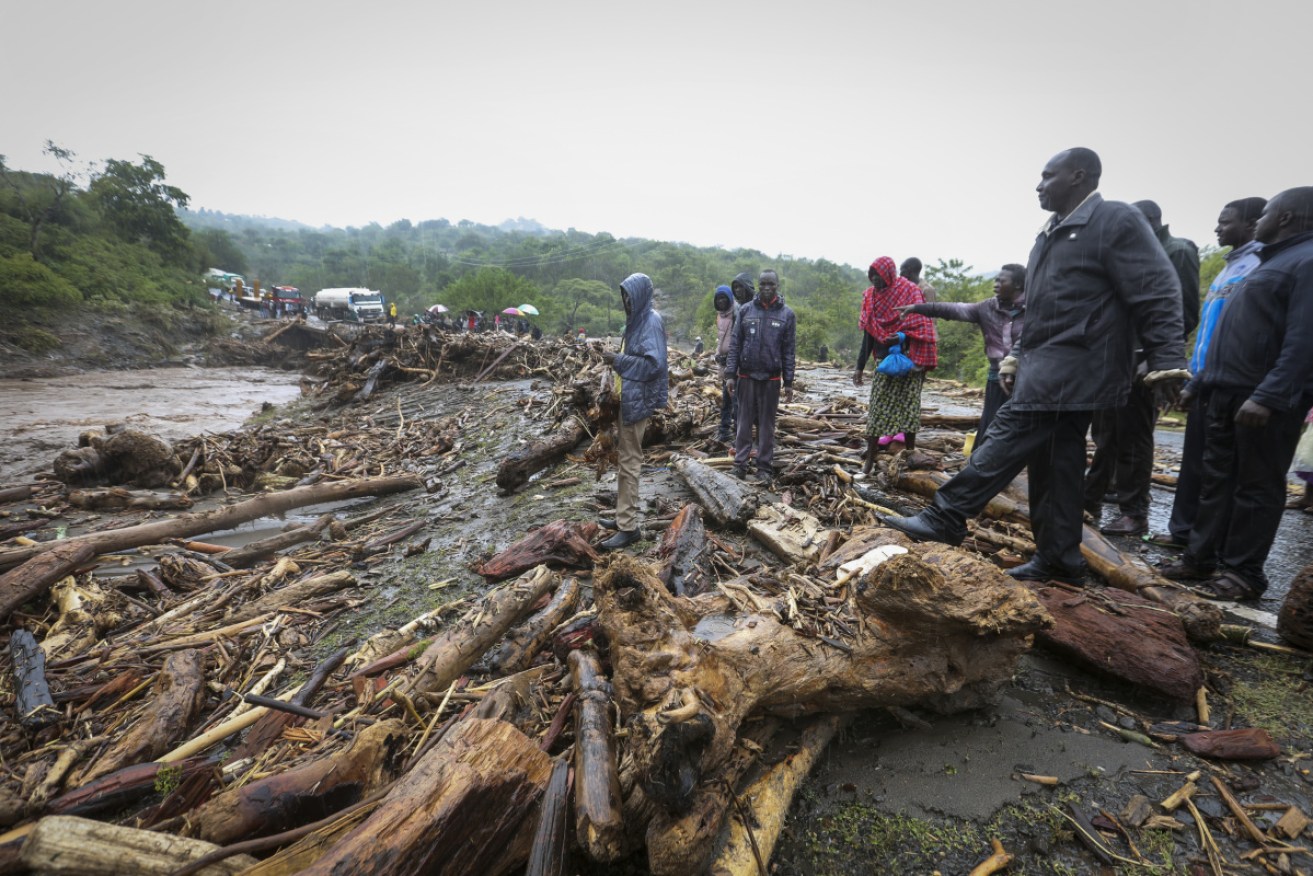 Passengers from stranded vehicles stand next to the debris from floodwaters.