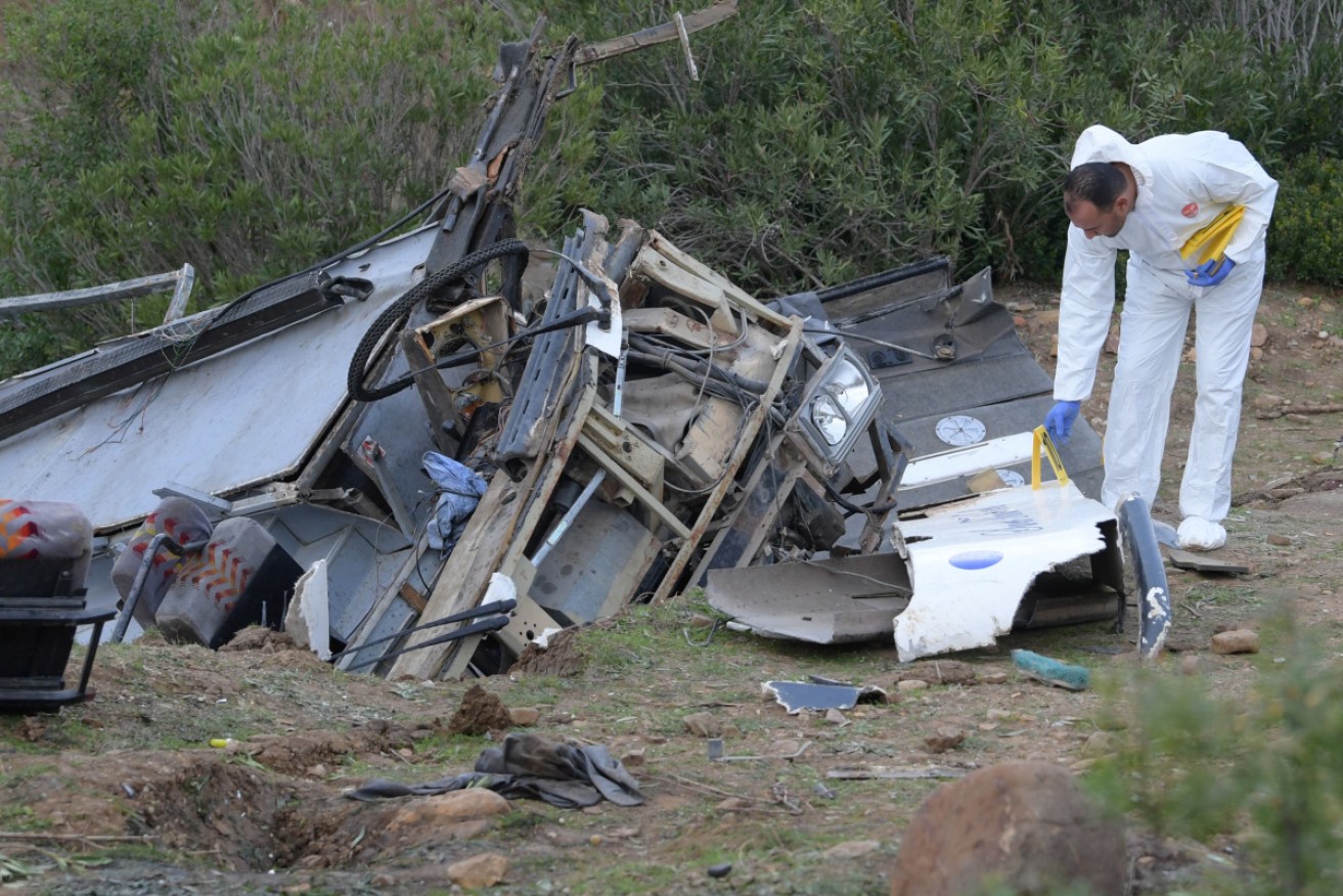 A forensic expert checks the debris of a bus that plunged over a cliff into a ravine.