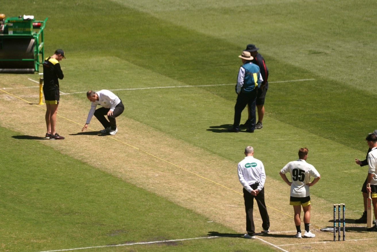 With play abandoned, ground staff, players and umpires inspect the troublesome MCG pitch. 