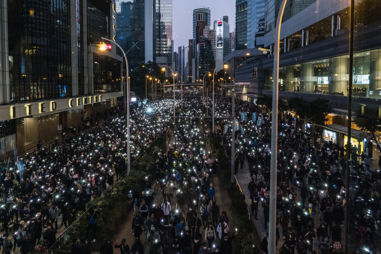 Demonstrators shine lights from their smartphones as they march along Queensway.