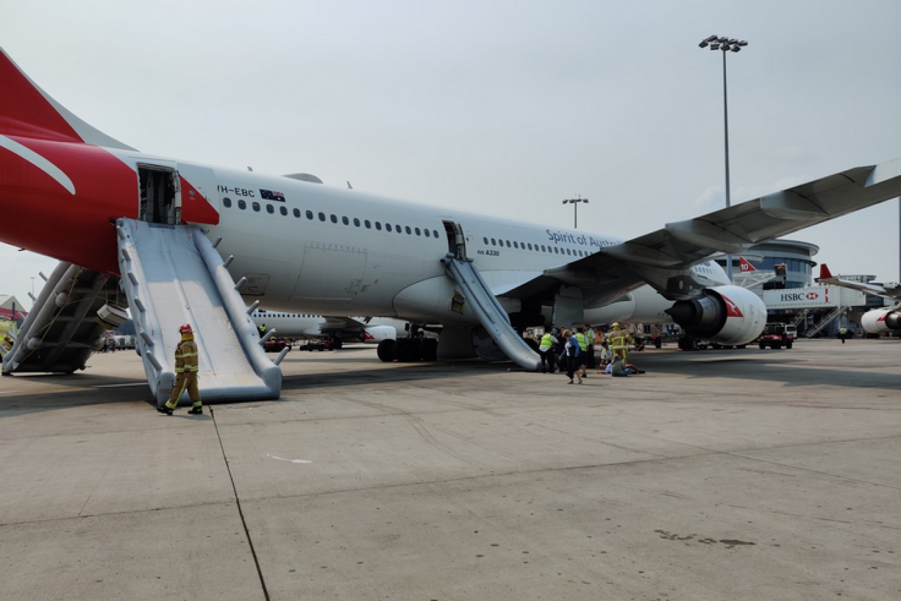 The qantas jetliner sits on the tarmac with its evacuation slides still deployed.