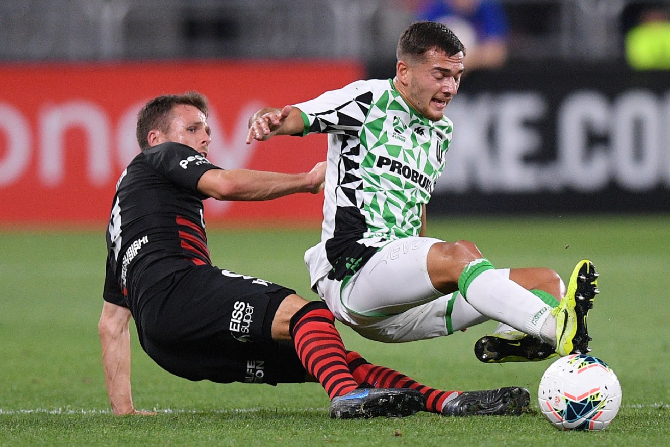 Tough night: Ersan Gulum of United is tackled by Nicolai Muller of the Wanderers.