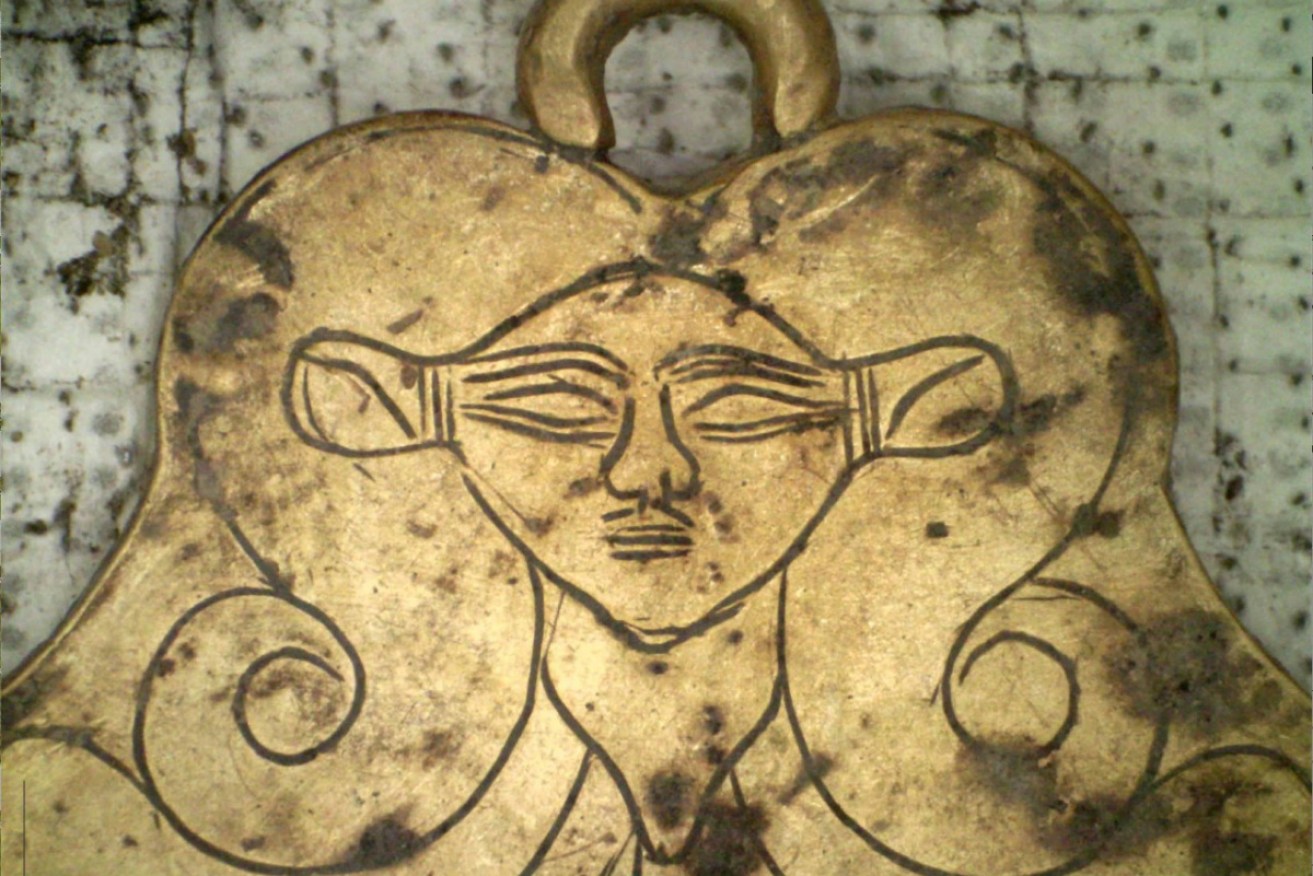 A gold pendant featuring the likeness of Hathor, an Egyptian goddess, a protector of the dead. 