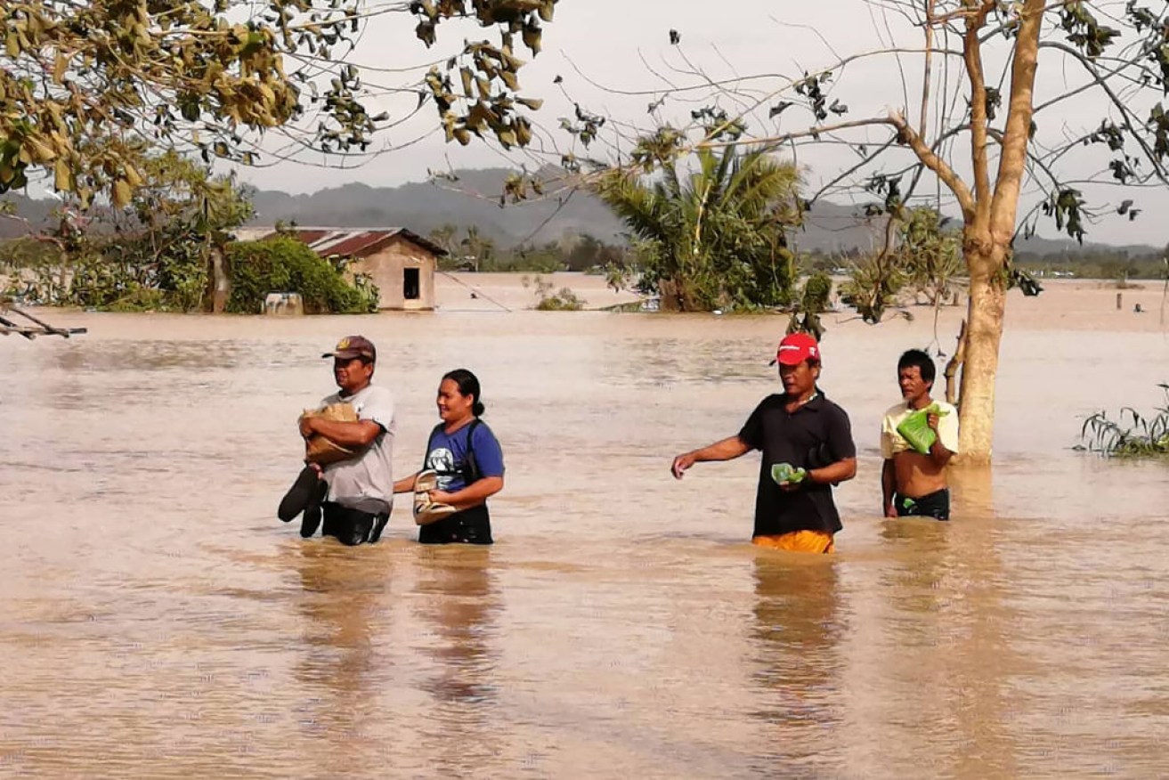 Residents wade through a flooded highway on Christmas Day, as Typhoon Phanfone hit Ormoc City, Leyte province in central Philippines on December 25, 2019. - Typhoon Phanfone pummelled the central Philippines.