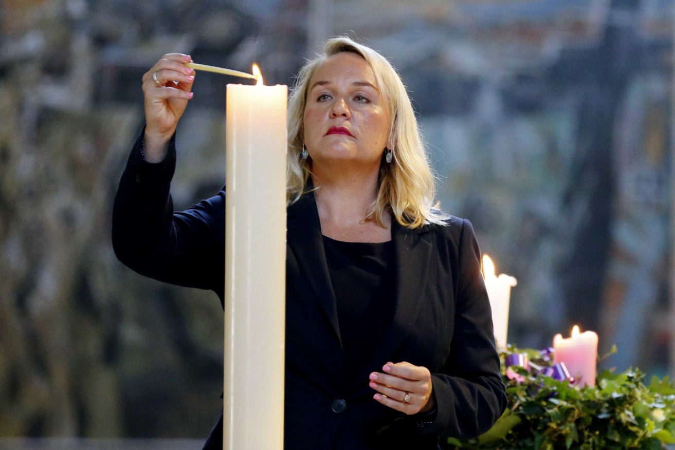 Newcastle mayor Nuatali Nelmes lights a candle during a service to commemorate the 13 victims who died in the 1989 earthquake.