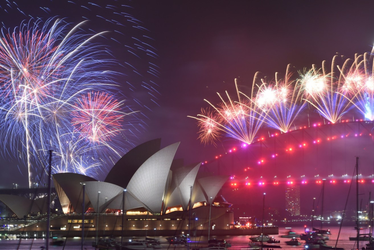 New Year's Eve fireworks erupt over Sydney's Harbour Bridge and Opera House (L) during the fireworks show on January 1, 2020.