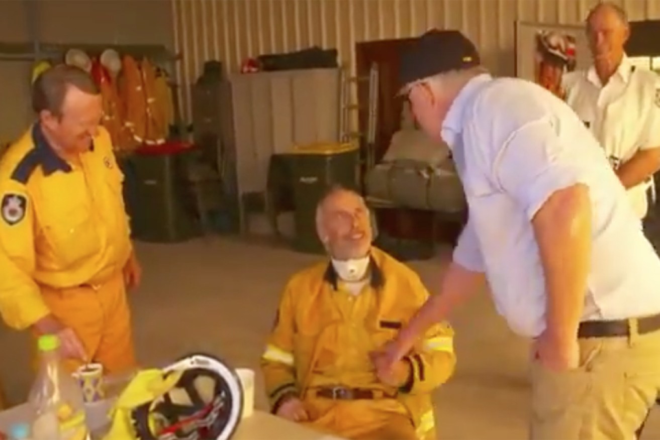 Scott Morrison attempts to shake the hand of a firefighter in Cobargo.