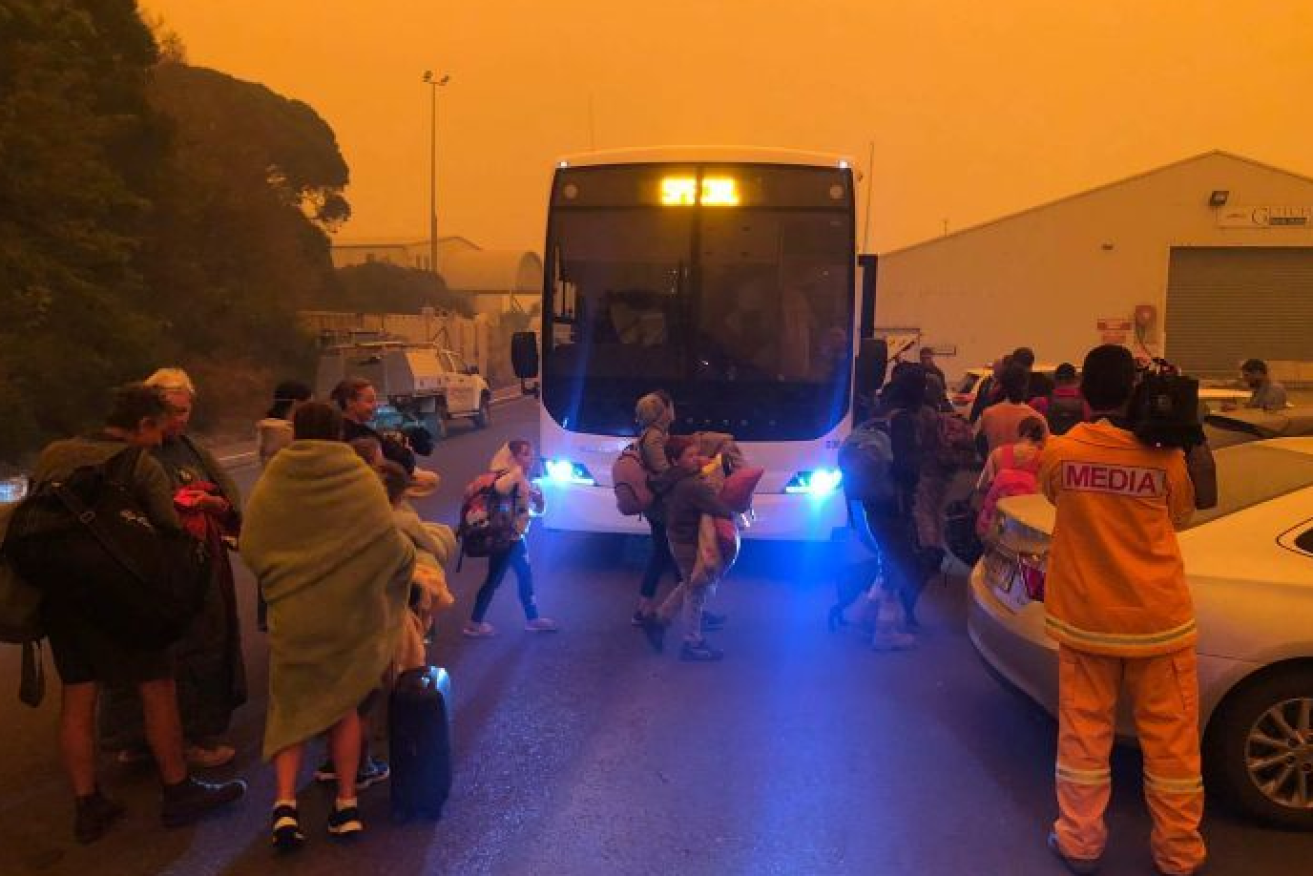 Eden residents board an evacuation bus  beneath the hellish orange sky.