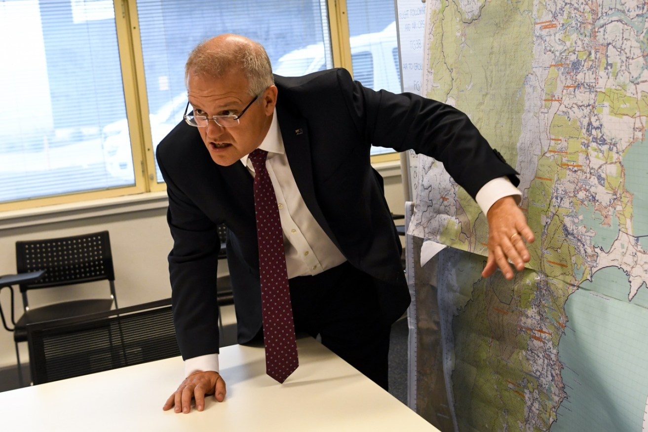 Prime Minister Scott Morrison takes a look at a map of the South Coast area impacted by bushfire during an operational update at HMAS Albatross in Nowra on Sunday. 