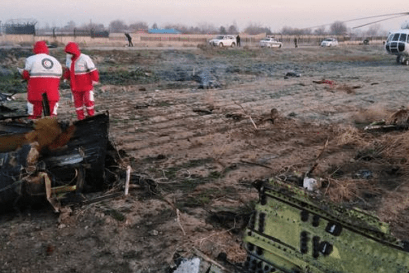 Recovery workers stand stunned in a bare field sown with death and debris.