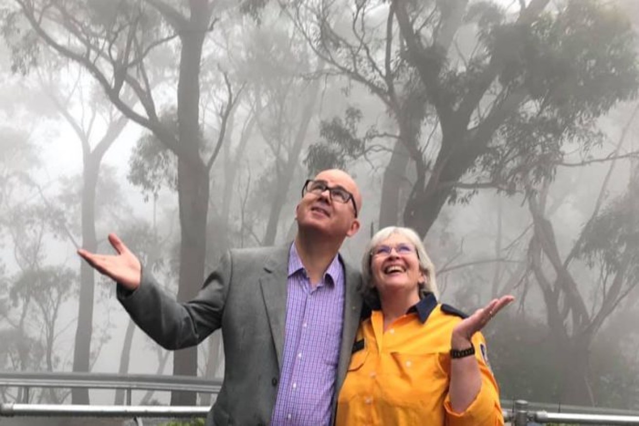 Mayor Mark Greenhill and a NSW RFS volunteer under the rain in the Blue Mountains on Saturday. 