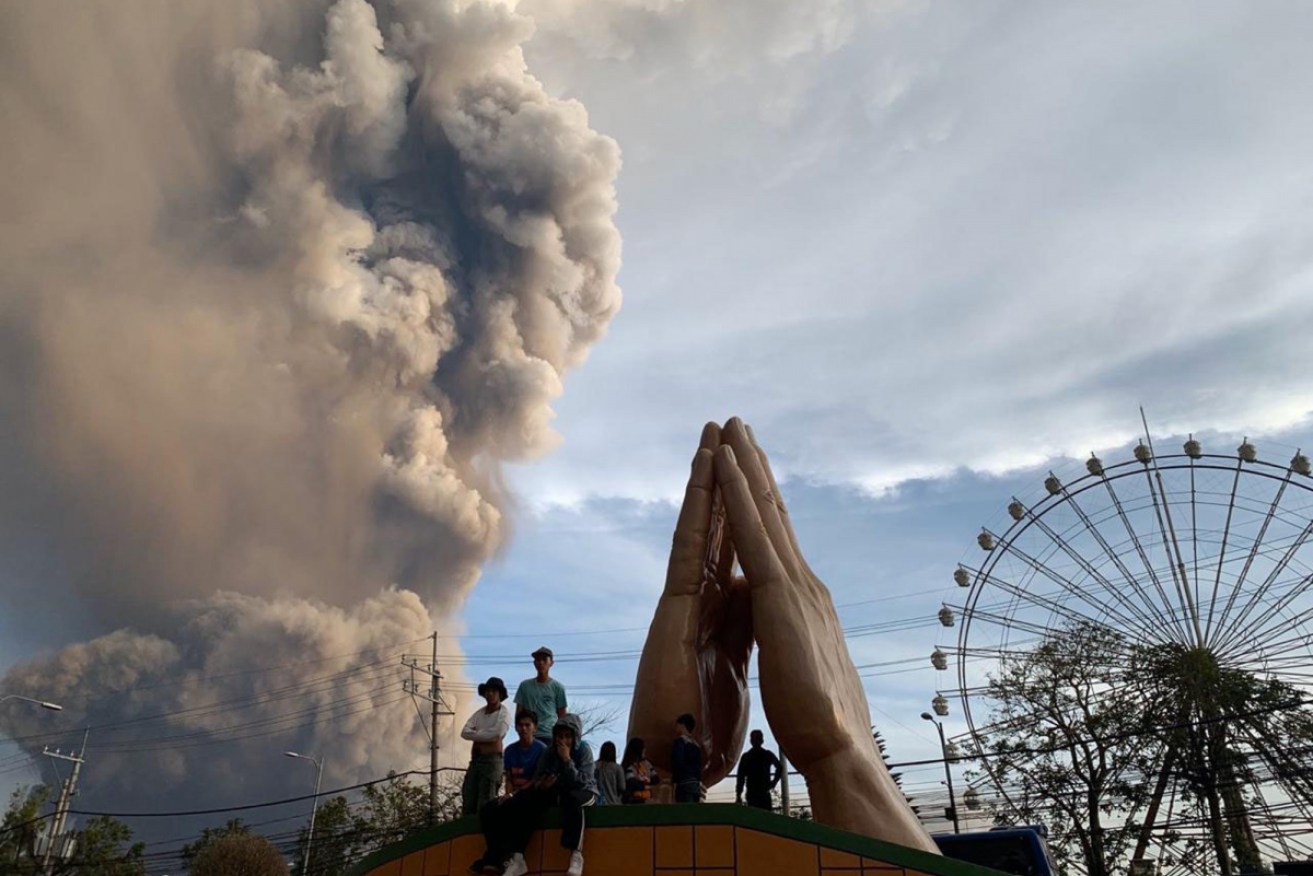 People watch as the Taal volcano spews ash and smoke on Sunday.
