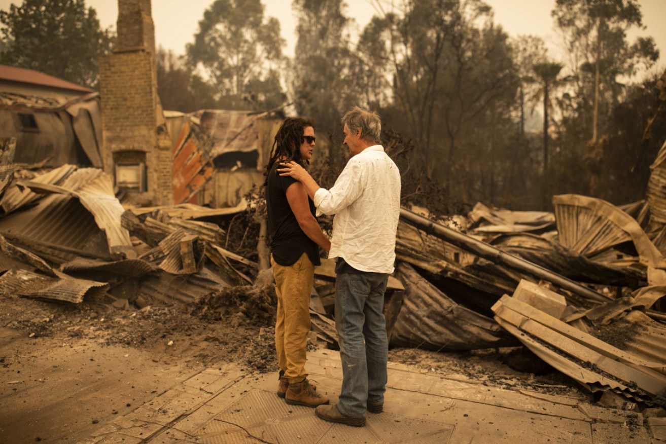 Business owner Sally Anne Wilson (left) stands in front of her destroyed shop with her partner Christopher Lee in Cobargo.