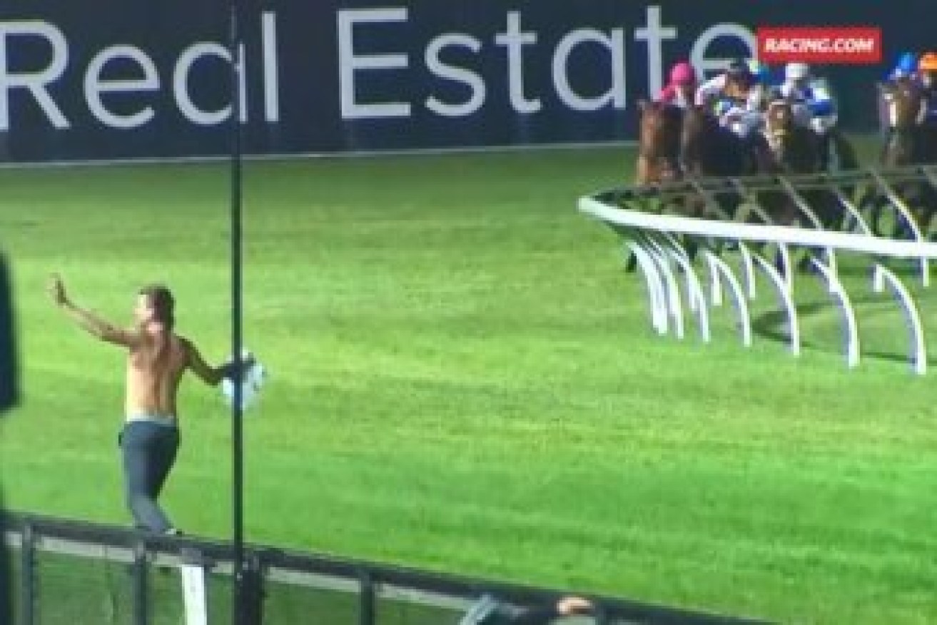 The shirtless man runs down the track as the horses thunder into the main straight. Photo: Racing.com