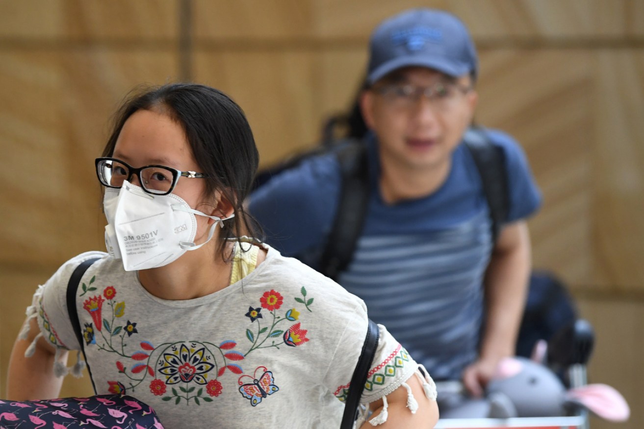 Passengers off the final flight from Wuhan to Sydney wear masks as they exit the airport on Thursday.