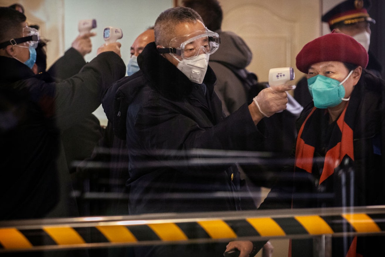 Chinese bullet train passengers from Wuhan to Beijing are checked for a fever by a health worker at a Beijing railway station.