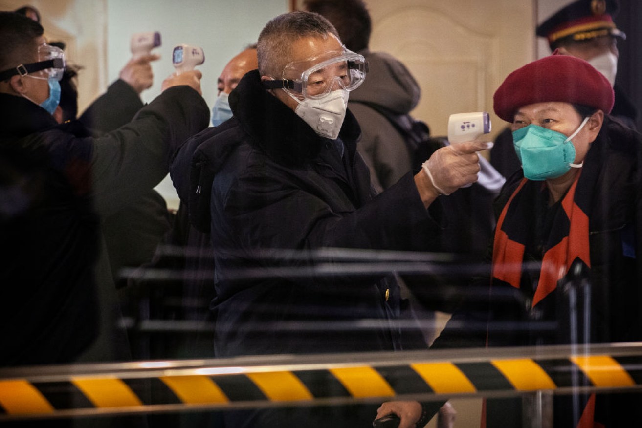 Chinese bullet train passengers from Wuhan to Beijing are  checked for a fever by a health worker at a Beijing railway station.