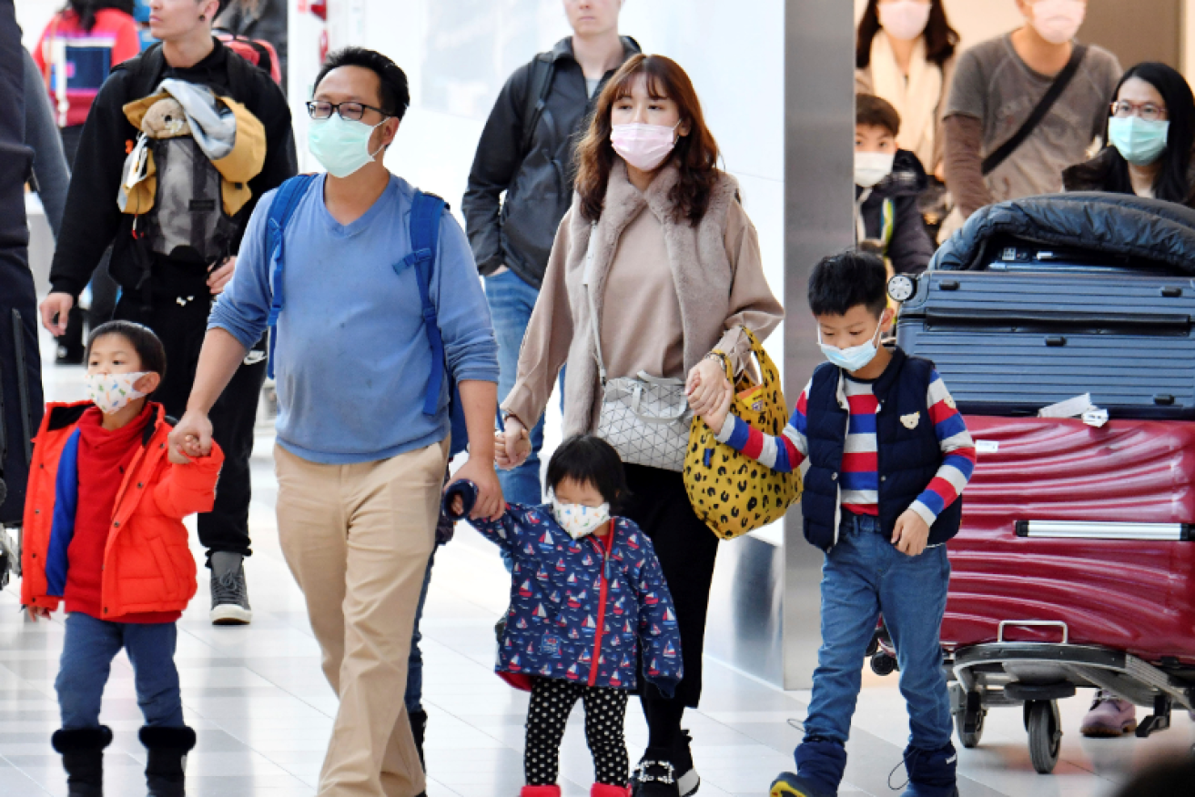 Masked passengers arrive in Hong Kong as the coronavirus - and the fear - spread through Asia and the world.