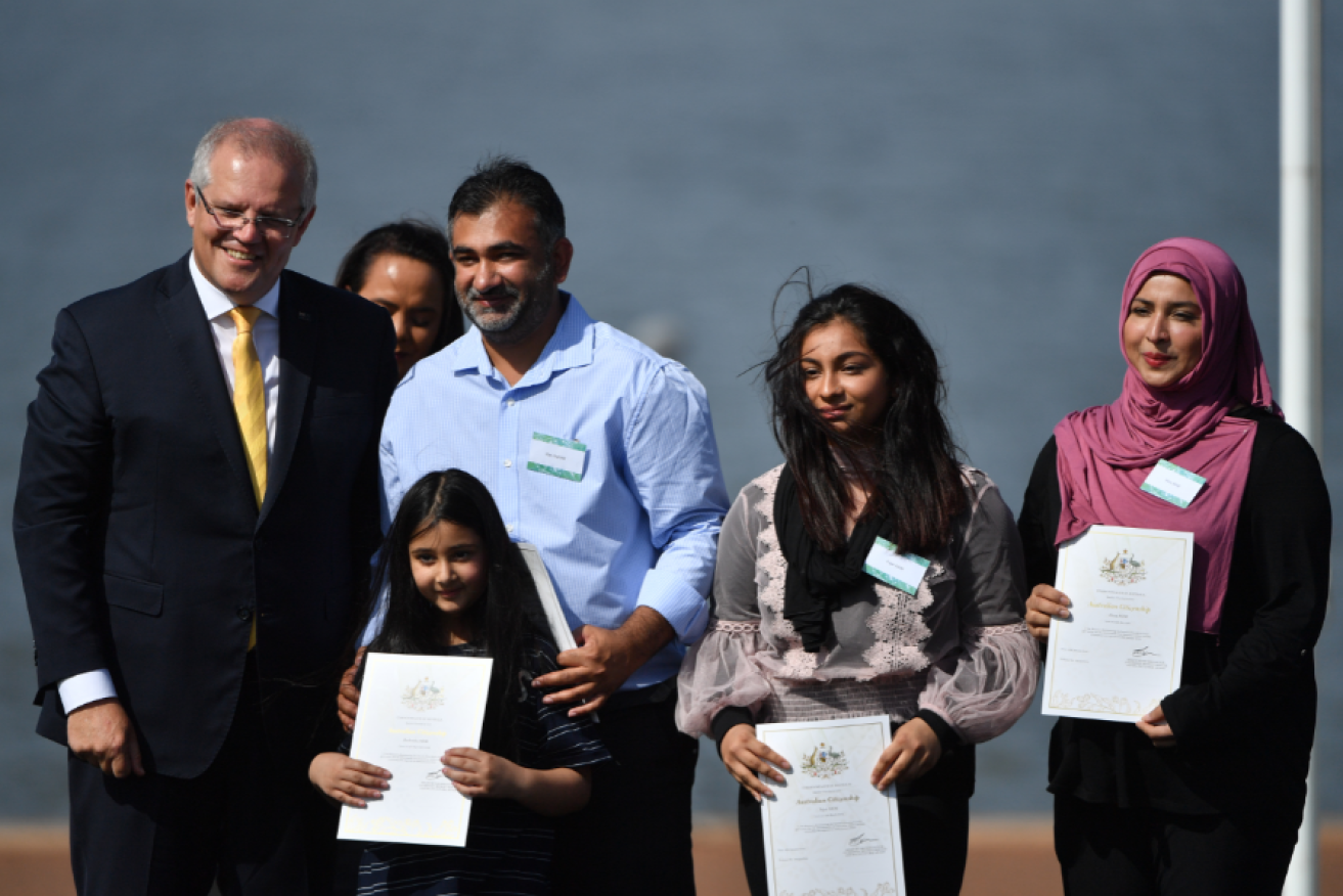 Scott Morrison gives citizenship certificates to Hina Asim (right) during an Australia Day Citizenship Ceremony in Canberra.