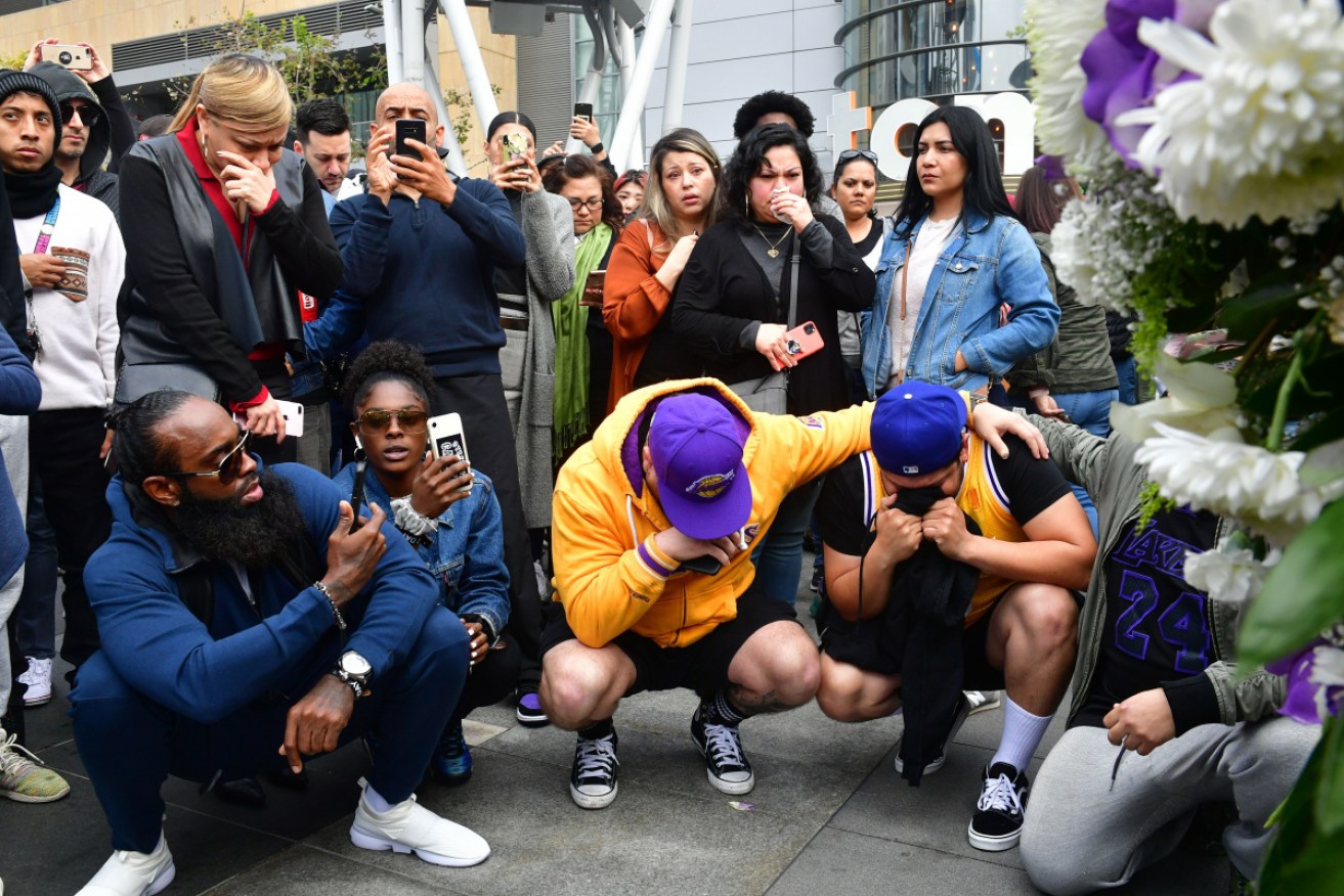 People gather around a makeshift memorial for former NBA and Los Angeles Lakers player Kobe Bryant after learning of his death at LA Live plaza in front of Staples Center in Los Angeles.