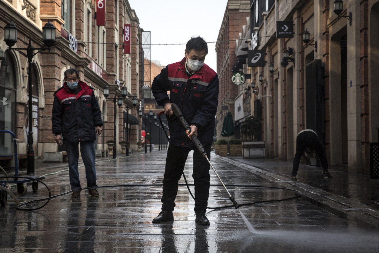 Cleaners wash the street with a high-pressure water gun during lockdown in Wuhan.