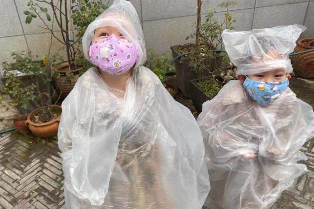 Siblings Orla and Orli in the protective clothing and masks they wear if they step out in coronavirus-stricken Wuhan.