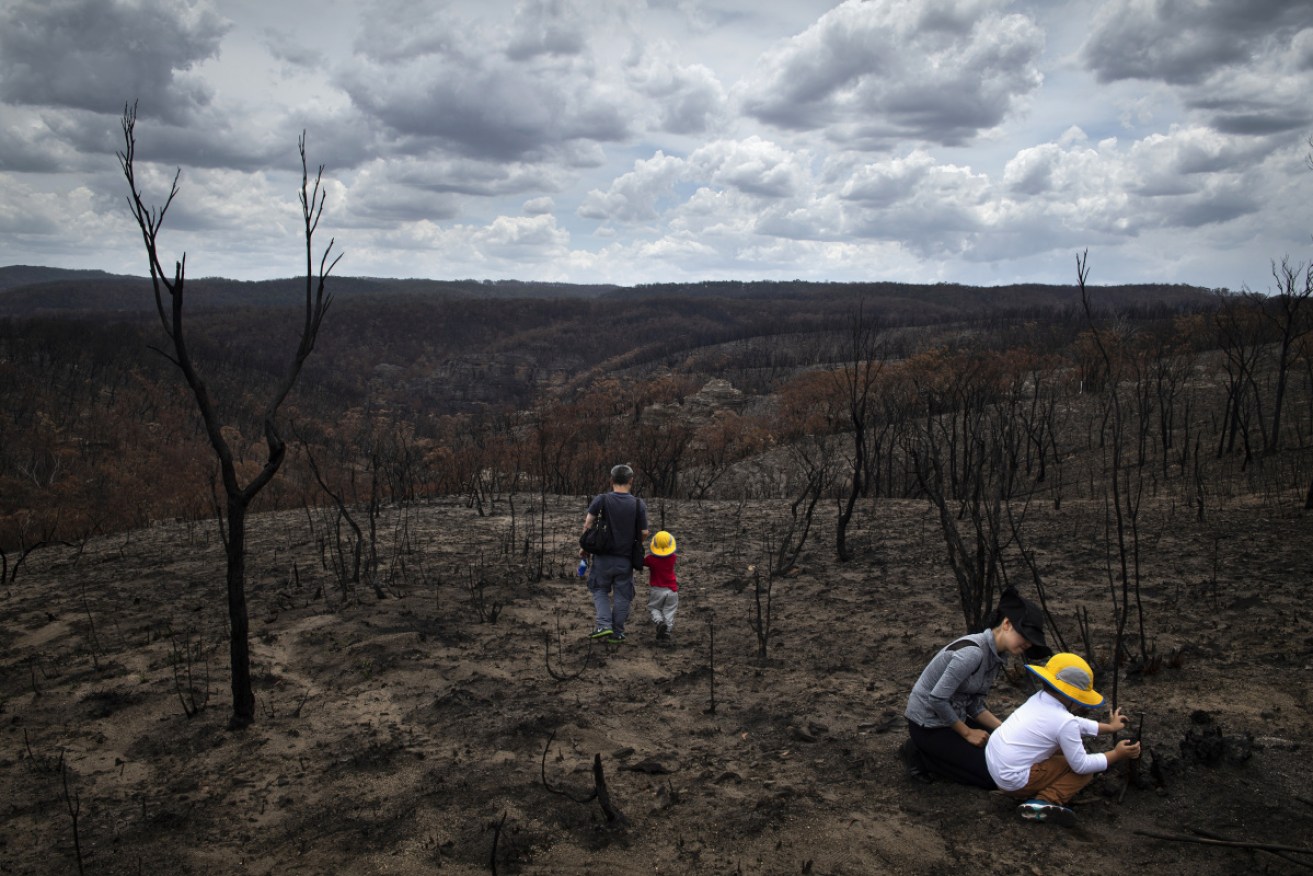 A family inspects the remains of a bushfire in Bell, New South Wales.