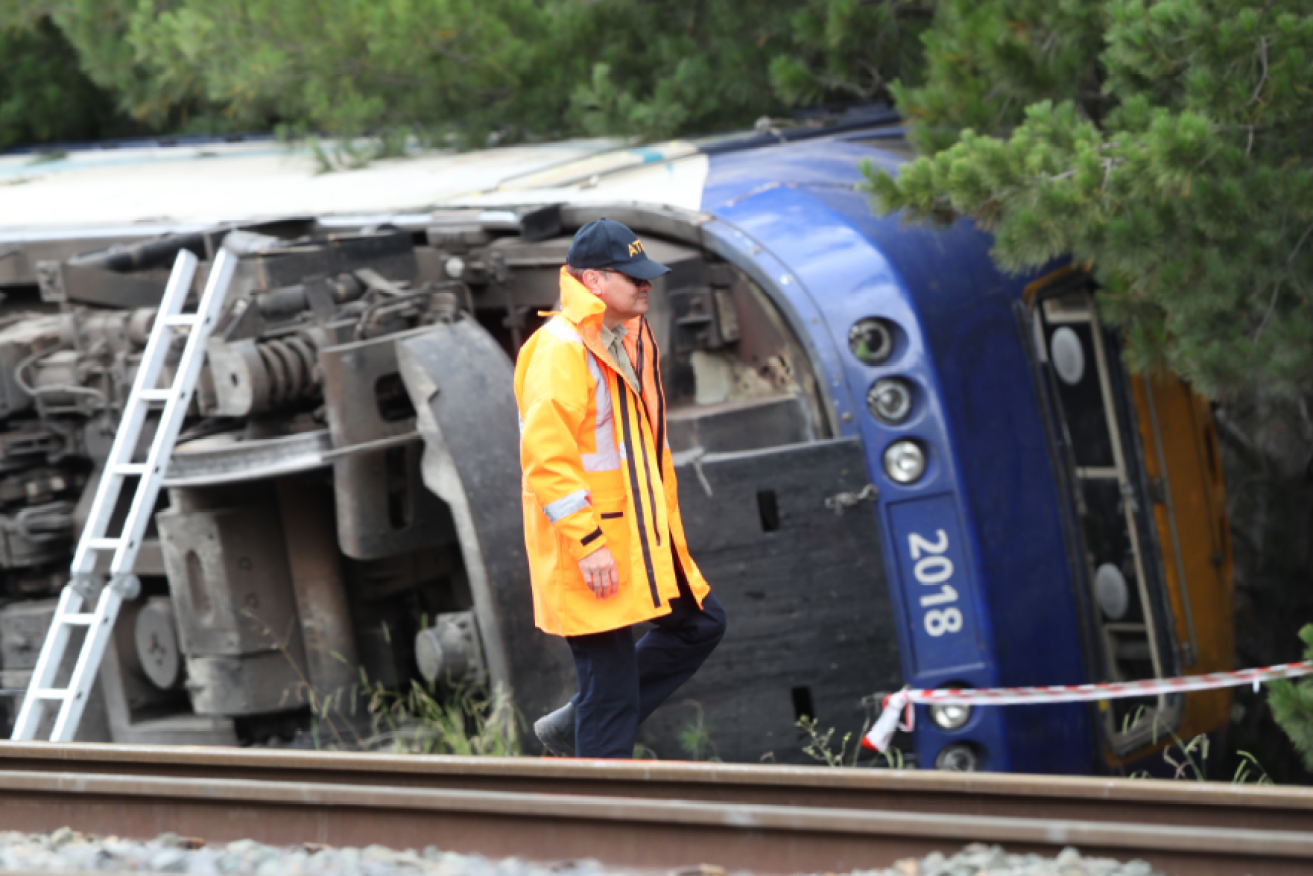 Dwarfed by the overturned locomotive, an ATSB investigator surveys the fatal wreck.