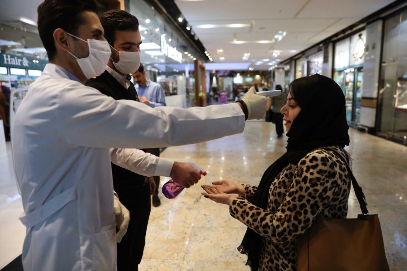 Health officials check a woman's temperature in Tehran, where coronavirus is raging.