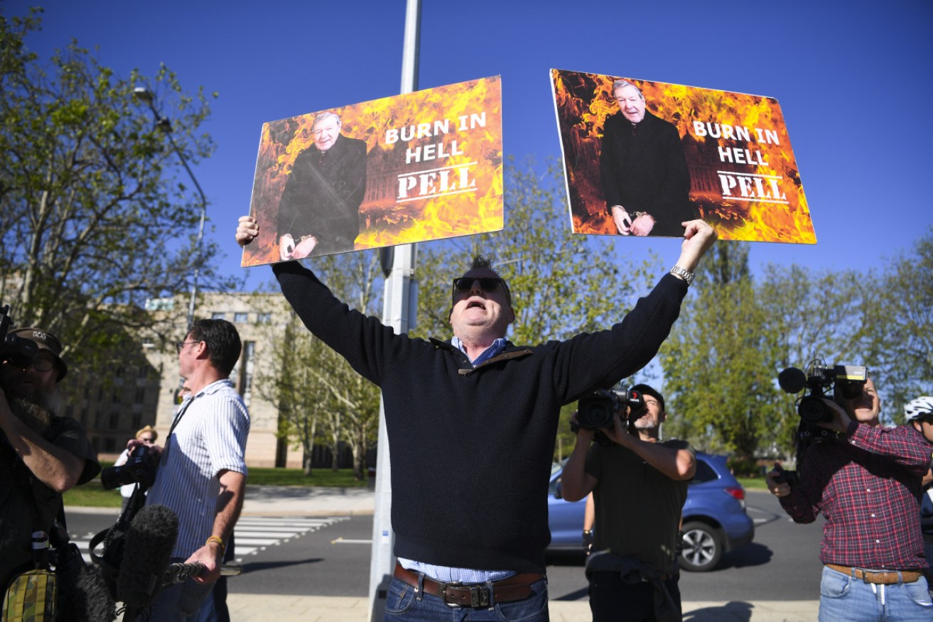 Child sex abuse victim Michael Advocate holds up placards outside the High Court of Australia.