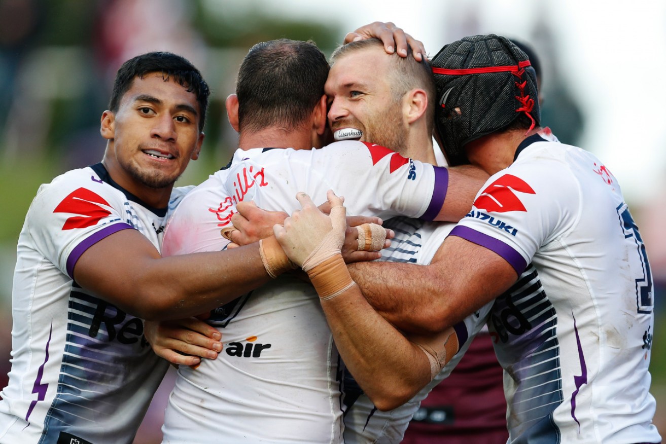 Tom Eisenhuth (centre) celebrates his try with Storm teammates. 